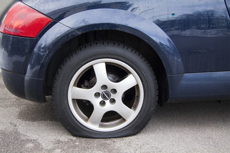 A flat tire on a car pulled over on the side of the road