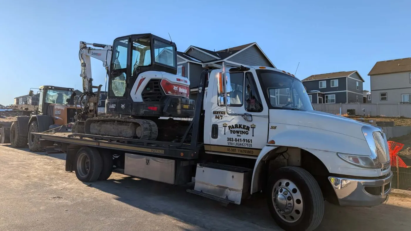 A Parker Towing flatbed hauling a Bobcat excavator on a Colorado job site